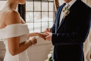 ALTER EGO NOTAIRES - Droit de la famille - Couple se mariant devant une fenêtre se passant la bague au doigt